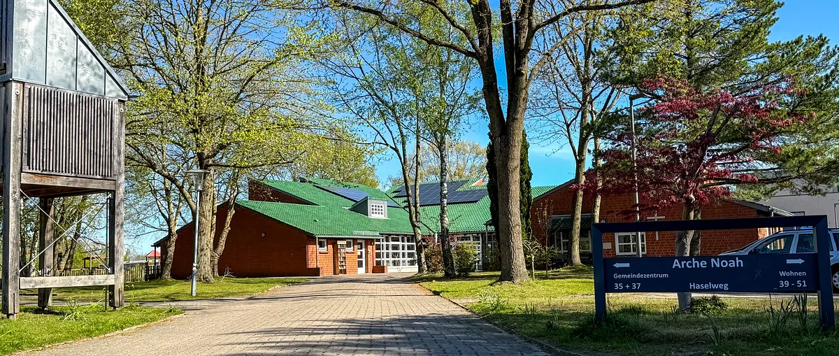 Gemeindezentrum Arche Noah mit Schild, Kirche und Parkplatz.