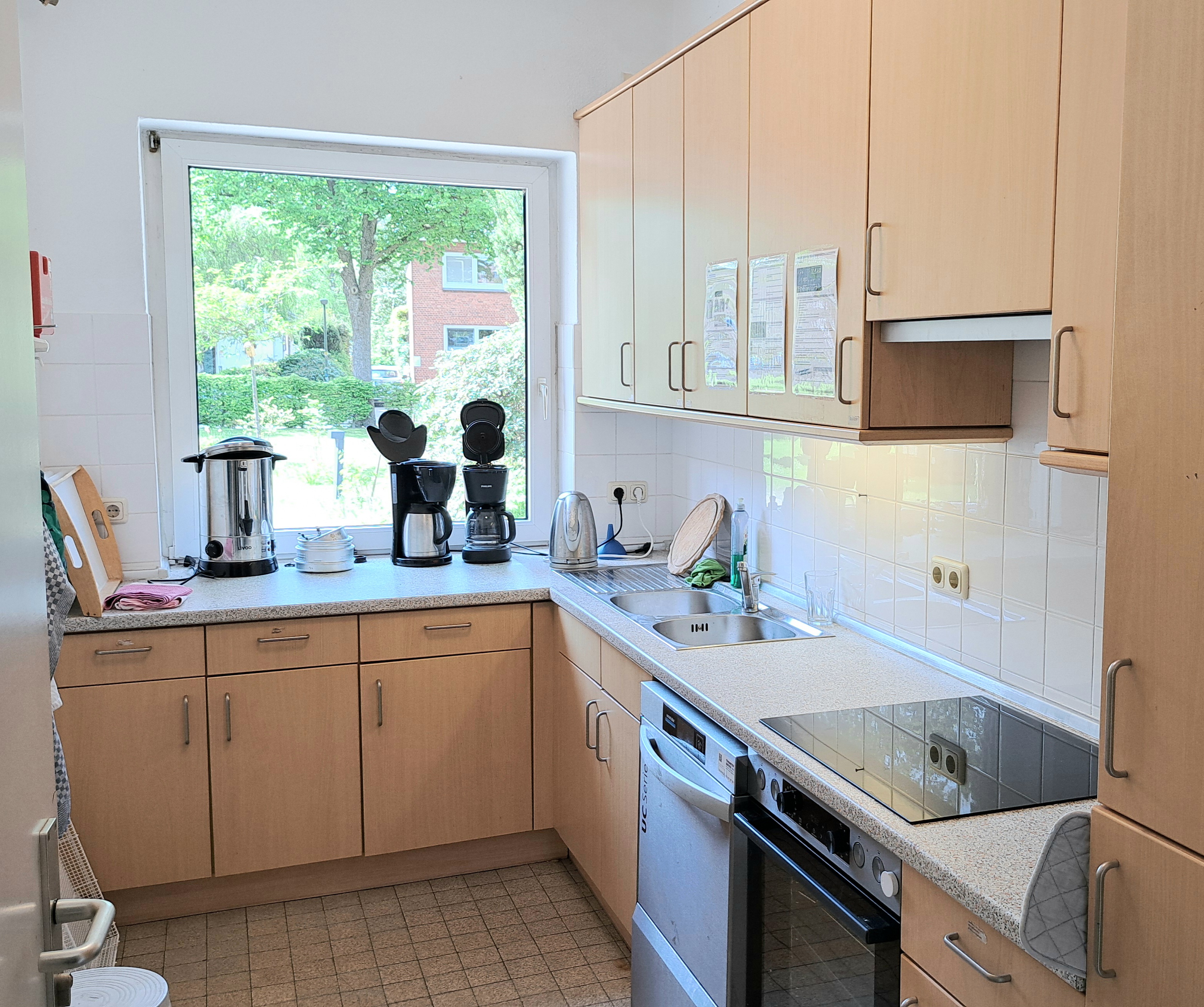 Helle Küche mit hellen Holzschränken und gefliestem Boden.