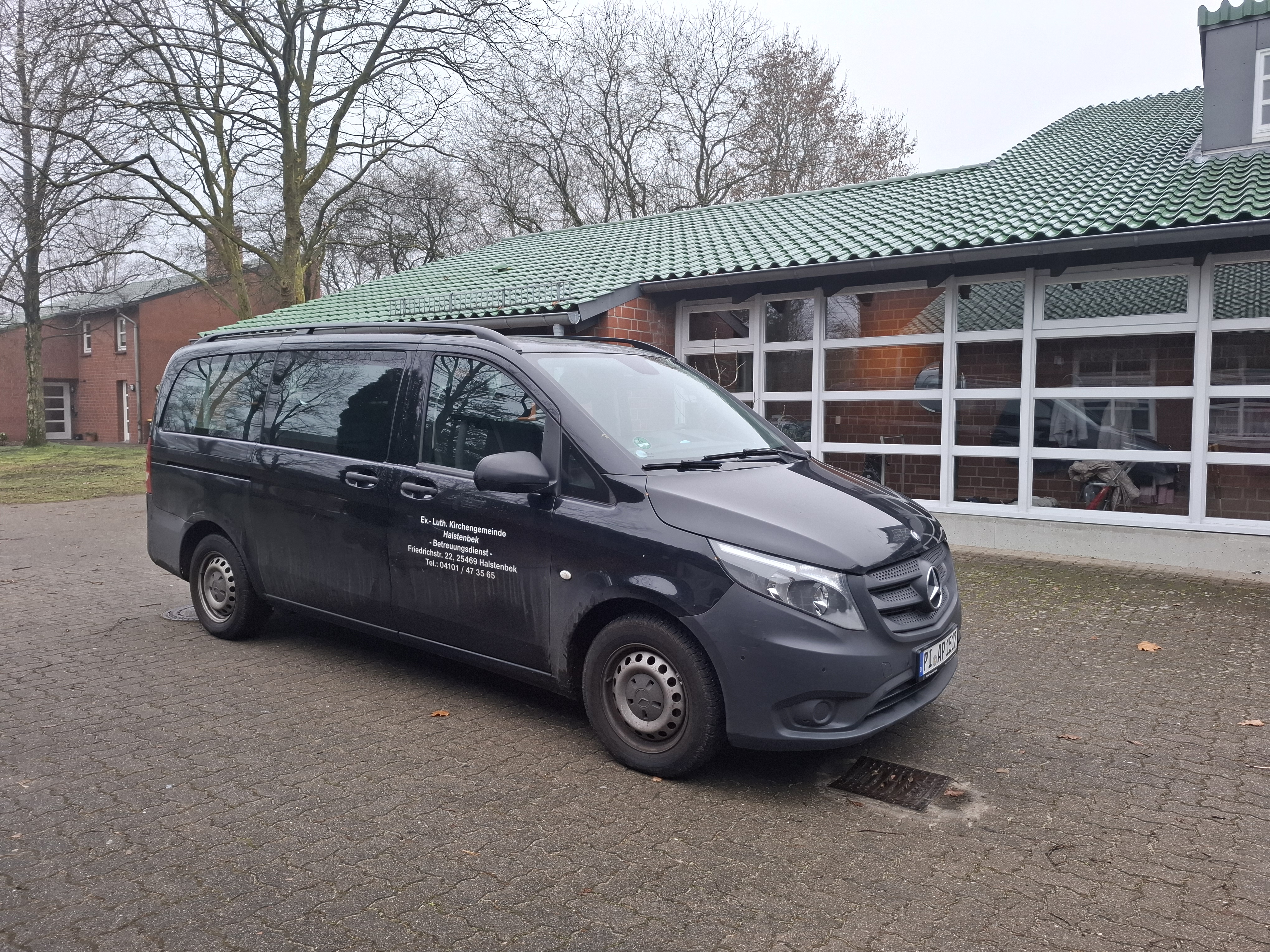 Dunkler Mercedes-Benz Vito parkt vor einem Backsteingebäude.