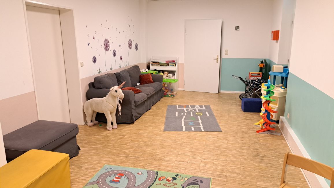 Gemütliches Spielzimmer mit einem grauen Sofa, das mit Überwürfen bedeckt ist.