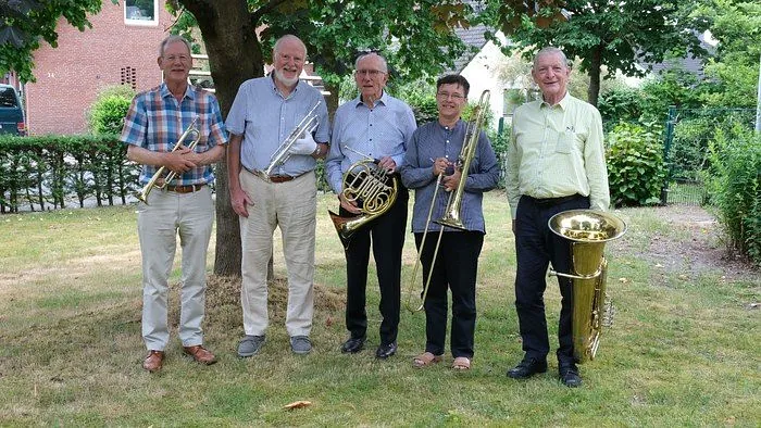 Fünf Musiker mit einer Trompete, einem Horn, einer Posaune und einer Tuba.