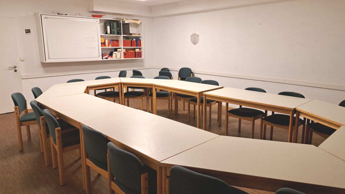 Besprechungsraum mit einem U-förmigen Tisch und blauen Stühlen.