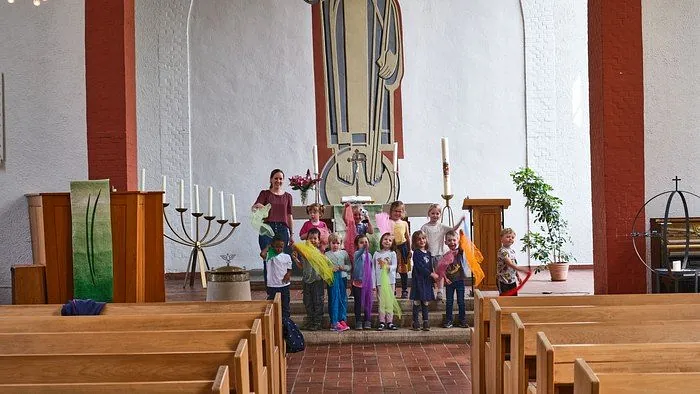Kinder mit bunten Tüchern und eine Frau in einer Kirche.