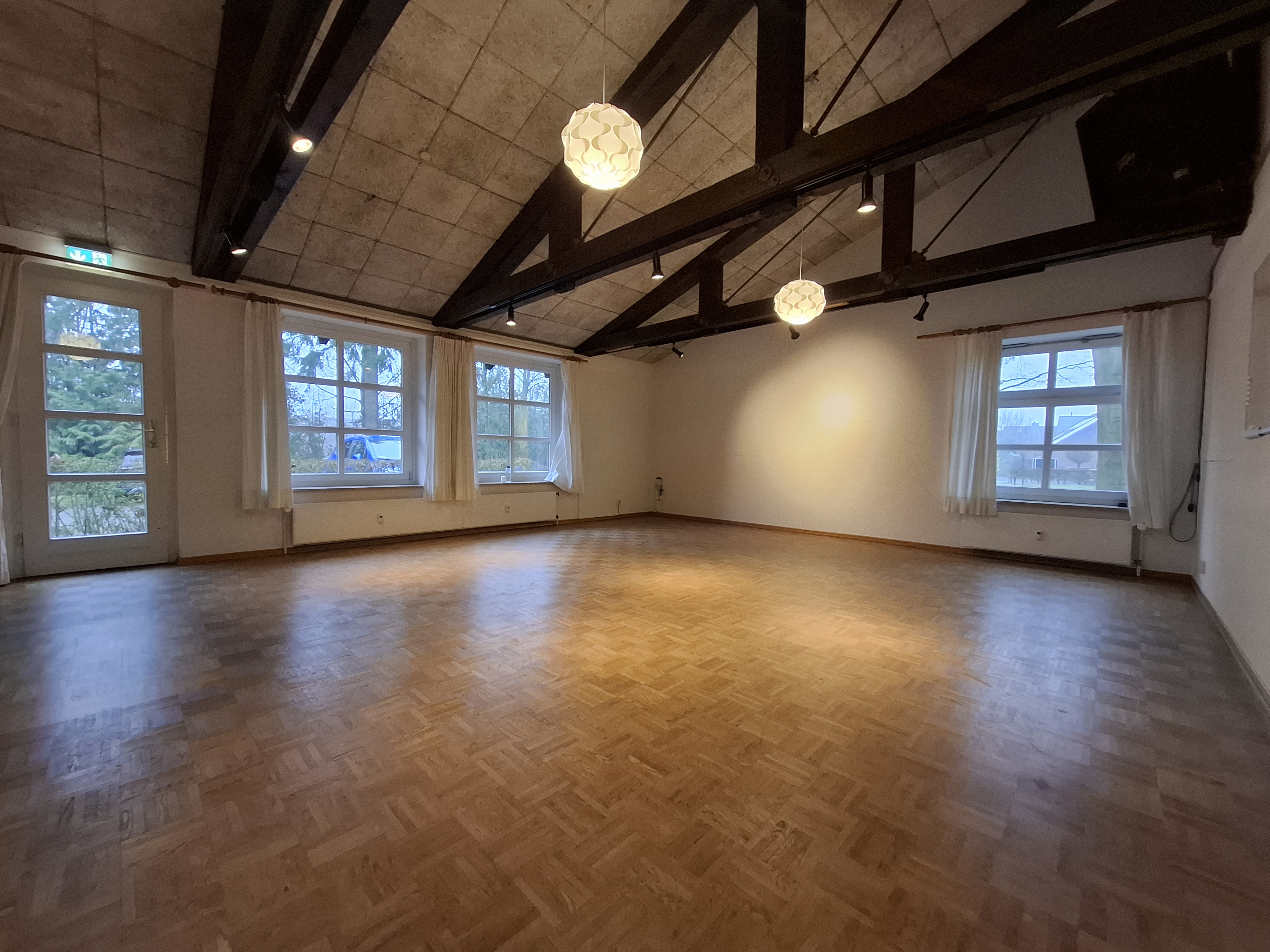 Geräumiger, leerer Raum mit Parkettboden und hoher Balkendecke.